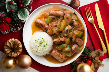 Sausages cooked with onion and pear. Top view table with Christmas decoration.