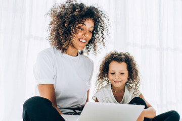 Fototapeta premium Lounging happy girl with mother using laptop
