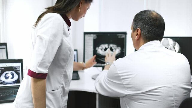 Specialists carefully analyze CT images on a computer in a modern diagnostic center. They provide accurate results and high-quality diagnostics, emphasizing exceptional patient care.