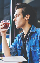 Stylish couple in love sitting coffee table in cafe and drinking juice during meeting.Young man and woman dressed in casual wear spending free time together in modern cafeteria interior