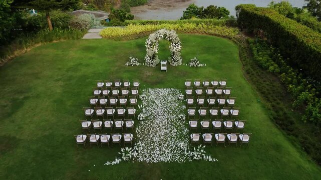Wedding setup and all decoration in the green garden Aerial drone top view of the wedding arch and chairs in garden near beach. Wedding ceremony with a decor on a green lawn.