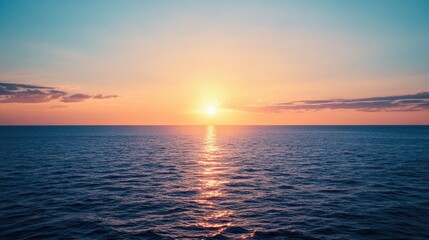 Obraz premium A serene sunset over the deep blue sea, with the sun casting a warm golden glow across the horizon, while the sky blends shades of orange and pink.