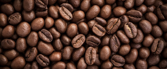 Freshly roasted coffee beans fill the frame. Classic background view from above. Premium background for coffee processing products.