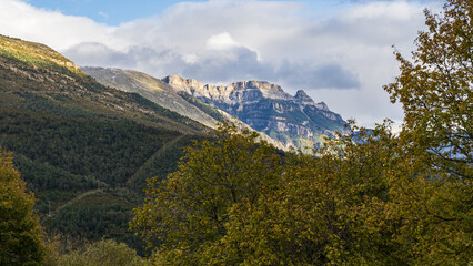 Fototapeta premium Mountain of the Aragonese Pyrenees surrounded by forests with cloudy sky.