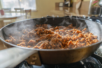Close up of ground meat in skillet with steam 