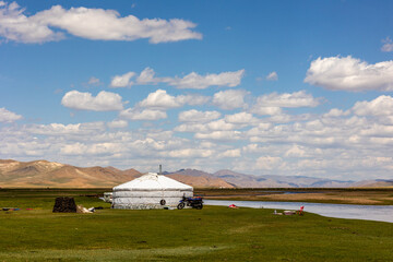 mongolian yurt at the river with blue sky and mountains
