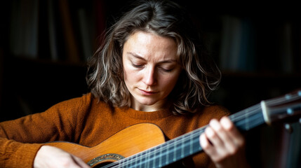 Fototapeta premium Focused woman playing acoustic guitar in a cozy setting