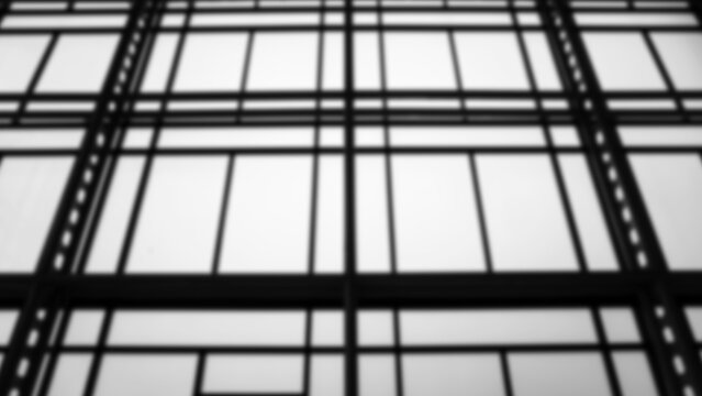 Black and white blurred image of the structure and glass of an office building..