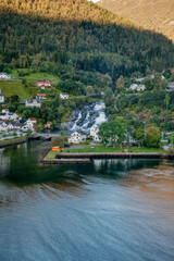 Naklejka premium A picturesque little village and a stunning, majestic waterfall, located by the beautiful fjord