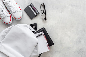 Flatlay of white backpack with wallet and bank cards and sneakers