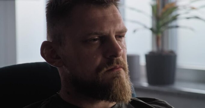 Portrait of depressed military man with PTSD crying, closing his eyes, remembering the war during rehabilitation therapy session with psychotherapist or psychologist. Post traumatic stress disorder.