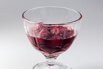 Strawberry jam in glass dessert bowl, side view close-up