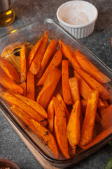 Appetizing sweet potatoes, cut into slices, baked in the oven with spices and butter close-up. Healthy vegan food. Selective focus. Vertical photo