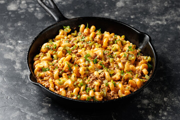 Cheeseburger Pasta with ground beef, melted cheese and gherkins in a iron cast pan