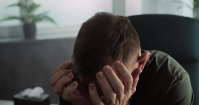 Portrait of depressed military man with contusion or PTSD crying during rehabilitation after war or counseling session. Warrior talks to psychotherapist or psychologist. Post traumatic stress disorder