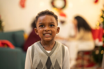 A close up portrait of a young boy smiling during a festive Christmas gathering. The soft bokeh from holiday lights and decorations in the background creates a warm and joyful atmosphere.