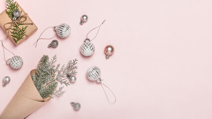 Christmas banner, postcard, greeting. Cone bag with fir branches and Christmas glass Christmas tree balls and gift box on pink background.