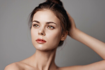 Fototapeta premium Young woman poses with hands on head against gray background in a photo illustration