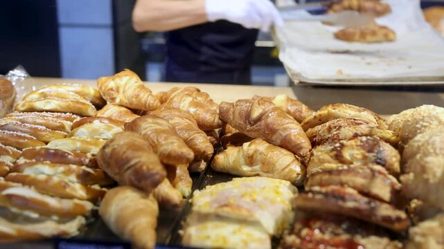 Pastry Shop Vendor Arranging Croissants in Display Case with Tongs
