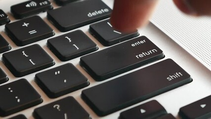 Slow motion of forefinger pressing enter key on modern laptop computer keyboard, extreme closeup macro detail, shallow DOF, one person. Sending messages, purchasing, receiving rules, executing program