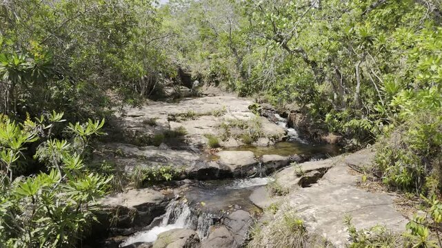 Drone flies backwards and pans down over Cachoeira 7 de Setembro in the Parque Nacional da Chapada dos Guimar&atilde;es, Mato Grosso, Brazil