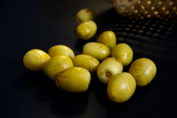 Date palm fruits placed on black background with blur basket on the back. Close-up date palm texture in dark theme. Fresh fruit, healthy, tropical, and rustic kitchen concept. Food image of date palm.