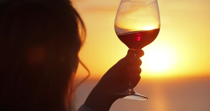 Slow motion silhouette woman tasting wine at the sea sunset