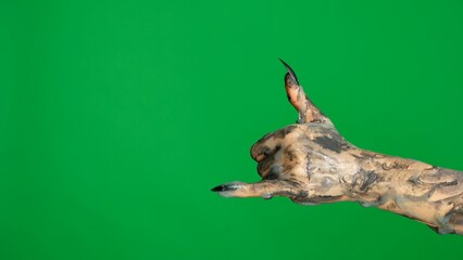 Creepy Halloween monster hand in black paint with fingernails showing a call me sign, isolated against a green screen background with a chroma key, workspace mockup.