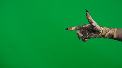 Creepy halloween monster hand in black paint with nails moving pointing finger at side, isolated on chroma key green screen background, workspace mockup.