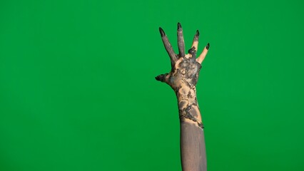 Creepy halloween monster hand in black paint with nails crawling, moving fingers isolated on chroma key green screen background, workspace mockup.