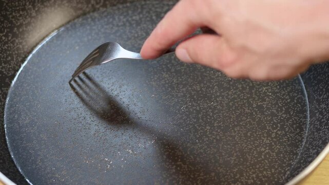 Pan peeling off. Fork in Scratched Teflon non-stick coated pan on stove. Dangerous chemicals in cookware.