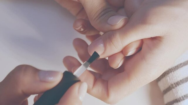 Manicurist painting her client's nails. Professional manicurist applying white nail polish to young girl's nails.