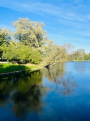 Beautiful blue lake in the park, sky and trees reflection on the lake surface