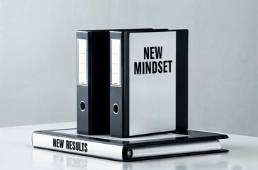 A set of three-ring binders with the text word "New Mindset" on the side, placed on a reflective surface