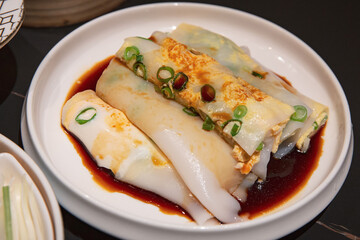 Delectable Chang Fen with egg, garnished with scallions and soy sauce, served in a white ceramic bowl for Yum Cha
