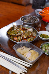 A traditional Cantonese home-cooked meal featuring steamed crabs, poached chicken, and seafood dishes, served with dipping sauces on a wooden table