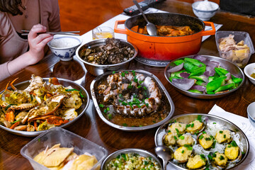 A traditional Cantonese feast featuring steamed crab, eel with black bean sauce, poached chicken, and a variety of vegetables, served on a family dinner table