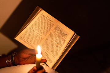 A young man meditating on the Bible in the dark with a candle