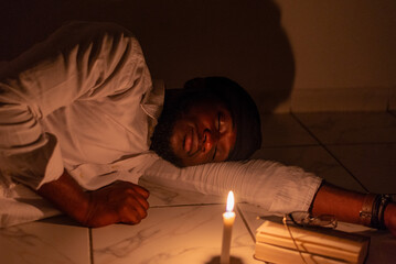 A young man meditating on the Bible in the dark with a candle