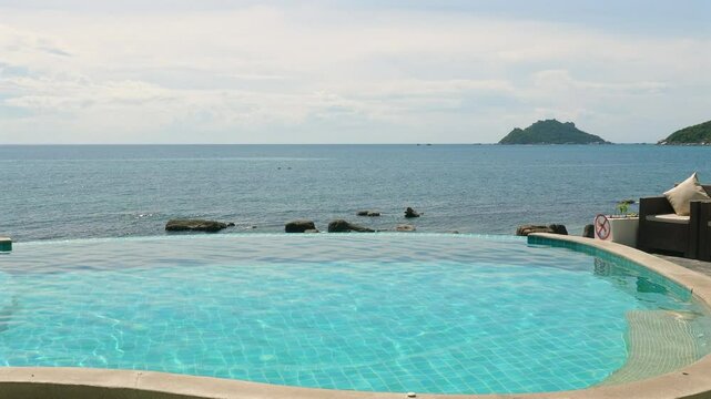 Scenic view of infinity pool overlooking serene ocean and distant island on sunny day. Relaxation and Tranquility.