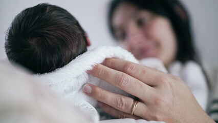Mother gazing lovingly at her newborn baby, supporting the child’s head with her hand, warm and intimate moment of connection and care, cozy home environment, soft light