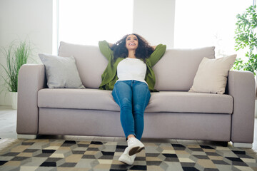 Photo of lovely cute dreamy girl hold arms behind head sit soft divan comfortable apartment flat indoors