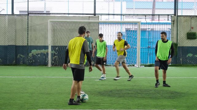 Group of young adults play soccer, training day on the football field, teenagers play football.
