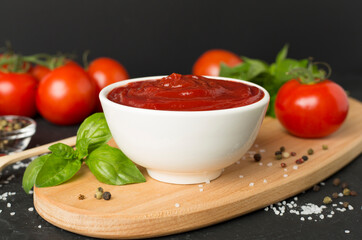 Delicious ketchup with spices and tomatoes on wooden table