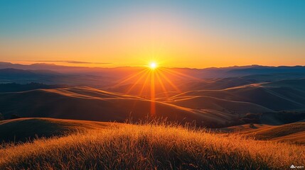 Stunning sunrise over rolling hills, casting warm light on golden grass, creating a tranquil and picturesque landscape.