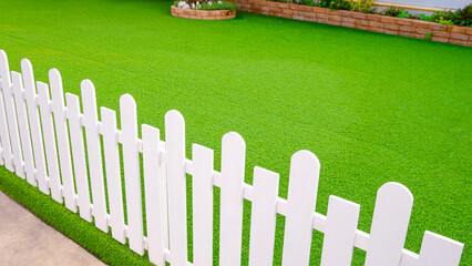 Artificial grass turf with white wooden picket fence in front yard area of vintage house, Home...