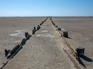 Fototapeta premium A wooden corridor through the flat bottom of a dried-up lake. Salt was mined here a hundred years ago. A good example of perspective, entering into one point
