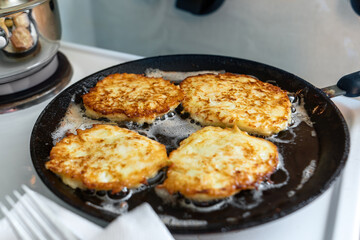 Golden zucchini pancakes sizzle in a hot skillet, their crispy edges contrasting with a soft, moist interior. Perfectly cooked, these delightful treats offer a wholesome twist on comfort food