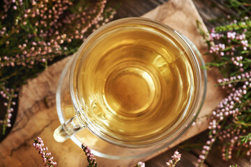 A cup of herbal tea with fresh heather or Calluna vulgaris flowers harvested in the forest