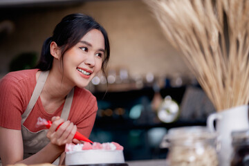 Chef making a cake at home. Homemade pastry shop. Happy young female pastry chef preparing a delicious birthday cake in the kitchen.
